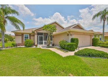 Beautiful single-story home with lush landscaping, palm trees, and a charming screened front porch at 2316 Lyndhurst Dr, Sun City Center, FL 33573