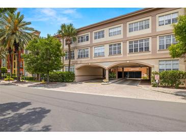 Beautiful building with large windows, a parking garage, brick entrance, and tropical landscaping at 2410 W Azeele St # 214, Tampa, FL 33609