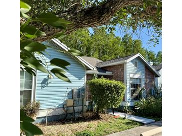 Charming home featuring a mix of blue siding and brick, complemented by lush greenery and mature trees at 5804 Red Cedar Ln # 5804, Tampa, FL 33625