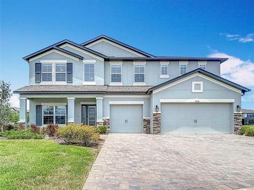 Gorgeous home featuring a three-car garage, beautifully designed facade, and pristine landscaping at 7628 Surf Reed Way, Wesley Chapel, FL 33545