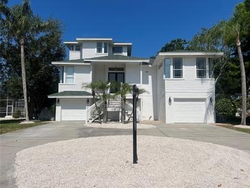 Charming two-story beach house with lush palm trees and a two-car garage in a tropical setting at 108 Peterson Ln, Palm Harbor, FL 34683