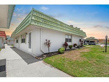 White home exterior featuring a vibrant green roof and well-maintained landscaping at 1802 Bedford Ln # 7, Sun City Center, FL 33573