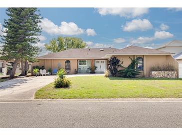 Charming single-story home features a well-manicured lawn and inviting front porch seating area at 1913 Libby Ct, Holiday, FL 34690