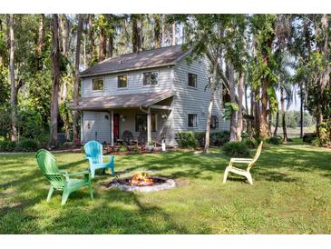 Charming two-story home with a fire pit and colorful Adirondack chairs on a spacious, lush green lawn at 22004 Dupree Dr, Land O Lakes, FL 34639