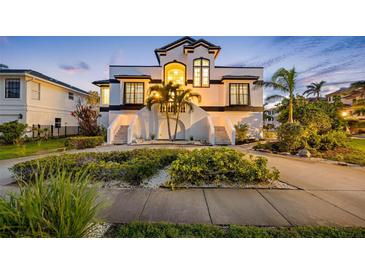 Elegant two-story home featuring lush landscaping, a symmetrical staircase entryway, and distinctive black and white accents at 6024 Kipps Colony E Dr, Gulfport, FL 33707