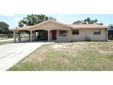 Tan single-story home features a carport, beige and rock facade, and well-lit porch at 6514 La Mesa Cir, Tampa, FL 33634