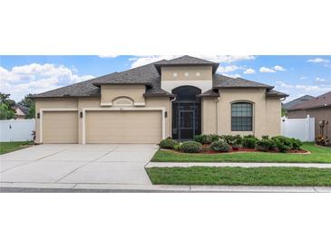 Charming home featuring a three-car garage, manicured landscaping, and a stylish architectural design at 8511 White Poplar Dr, Riverview, FL 33578