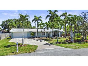 Charming single-story home with a well-manicured lawn and driveway, surrounded by tall palm trees at 10011 46Th W Ave, Bradenton, FL 34210
