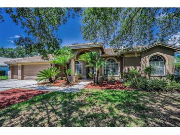 Stunning single-story home with lush landscaping, arched windows, and a terracotta roof at 1516 E Lake Woodlands Pkwy, Oldsmar, FL 34677