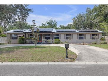 Charming single-story home with solar panels, neutral paint, mature landscaping, and a circular driveway at 2704 Dorene Dr, Plant City, FL 33563