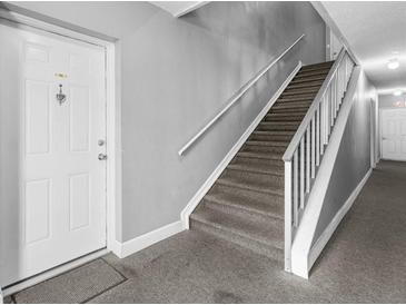 View of a carpeted stairwell in a home with a white front door at 9130 Tudor Dr # M105, Tampa, FL 33615