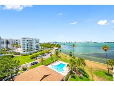 A beautiful view of the community pool with palm trees and the bay in the background at 100 Oakmont Ln # 802, Belleair, FL 33756
