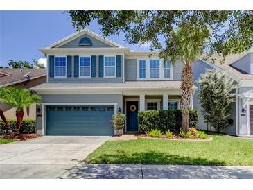Charming two-story home with blue accents, manicured lawn, and lush landscaping at 11606 Quiet Forest Dr, Tampa, FL 33635