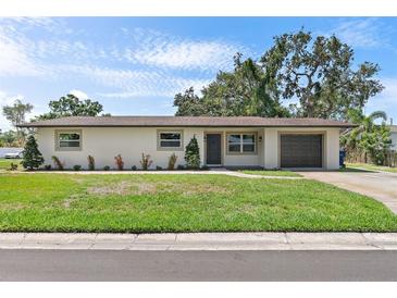 Charming single-story home boasts a well-manicured lawn, attached garage, and neutral exterior at 11764 Pinedale Ave, Seminole, FL 33772