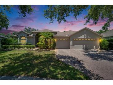 Charming single-story home showcasing a three-car garage, manicured lawn, and lush landscaping at 16367 Ashington Park Dr, Tampa, FL 33647