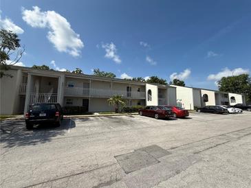 Condominium exterior showcasing ample parking and neutral color palette under a sunny blue sky with clouds at 2625 State Road 590 # 913, Clearwater, FL 33759