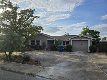 Charming single-story home with a well-maintained lawn and a one-car garage on a sunny day at 3333 Honeymoon Ln, Holiday, FL 34691