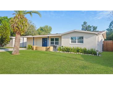 Charming home featuring a well-manicured lawn, inviting facade, and lush landscaping with a palm tree at 6334 Hyperion Dr, Port Richey, FL 34668
