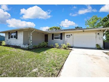 Charming single Gathering home with a brick facade, driveway, and front yard landscaping at 7810 Pineapple Ln, Port Richey, FL 34668