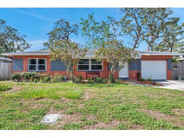 Charming single-story home with a well-manicured lawn, colorful flowers, and a cozy bench in front at 11348 59Th Ter, Seminole, FL 33772