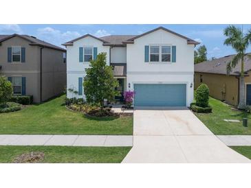 Charming two-story home boasts blue shutters, a well-manicured lawn, and an attached two car garage at 1203 Custer Bayou Street, Ruskin, FL 33570
