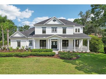 Stately two-story home showcasing a charming wrap-around porch and meticulous landscaping at 19803 Prince Benjamin Dr, Lutz, FL 33549