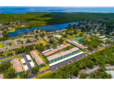 An aerial view of the community featuring lush landscaping, a pond, and a community pool and tennis courts at 255 114Th N Ave # 4, St Petersburg, FL 33716