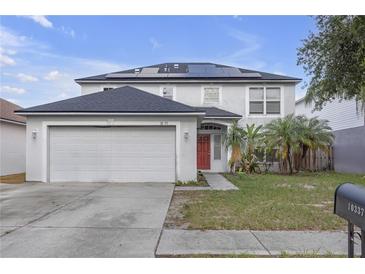Two-story home featuring an attached two-car garage, solar panels, and a red front door at 10337 River Bream Dr, Riverview, FL 33569