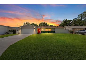 Charming single-story home featuring a well-manicured lawn, a red front door and sunset at 1546 69Th S Pl, St Petersburg, FL 33705