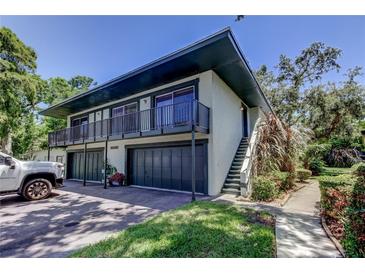 Two-story condo with garages, balconies, landscaped grounds, and exterior stairway at 2932 Lichen Ln # D, Clearwater, FL 33760