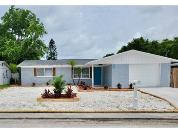 Charming single-story home featuring a blue exterior, well-manicured lawn, and a white garage door at 3401 Truman Dr, Holiday, FL 34691