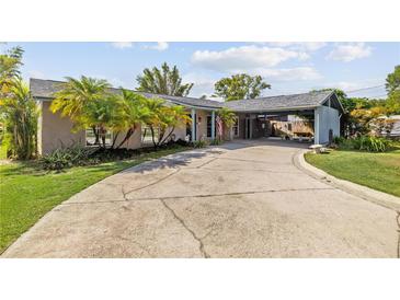 Charming single-story home with a long driveway, carport, lush landscaping, and lovely curb appeal at 5109 Vinson Dr, Tampa, FL 33610