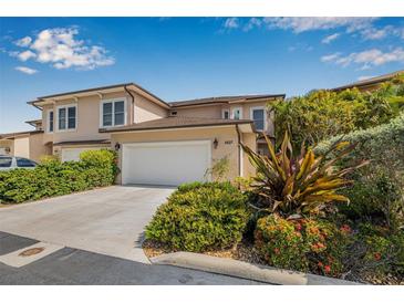 Two-story home with a two-car garage surrounded by lush landscaping including tropical plants and colorful flowers at 6627 Date Palm S Ave, St Petersburg, FL 33707