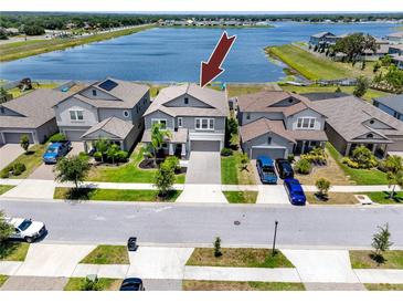 Aerial view of two-story gray home with manicured lawn and lake view at 11320 Chilly Water Ct, Riverview, FL 33569