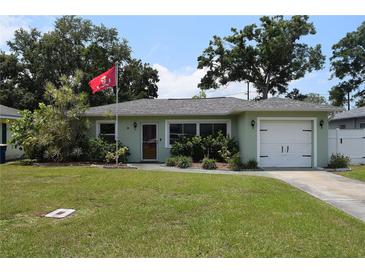 Single-story home featuring a well-maintained lawn and an attached garage at 1665 Grove St, Clearwater, FL 33755