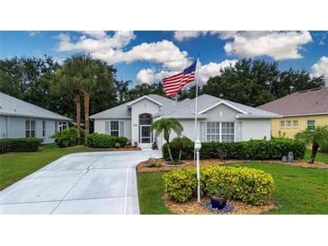 Charming single-story home featuring a well-manicured lawn, tasteful landscaping, and an American flag at 2121 Worthington Greens Dr, Sun City Center, FL 33573