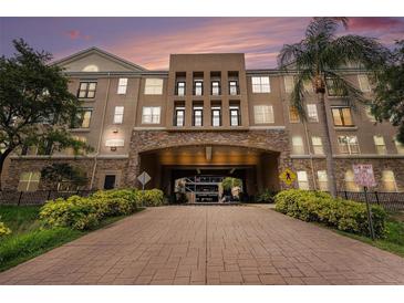 Condo building with landscaped entrance and parking garage access on a sunny day at 4221 W Spruce St # 2104, Tampa, FL 33607