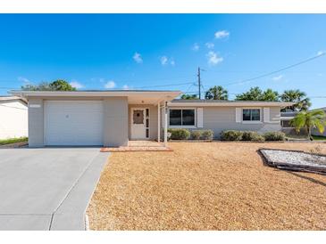 Charming single-story home featuring a well-maintained front yard and attached garage at 4842 Odyssey Ave, Holiday, FL 34690