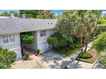 A two-story townhome with an attached garage, paved driveway, and mature trees and landscaping at 1211 W Horatio St # A, Tampa, FL 33606