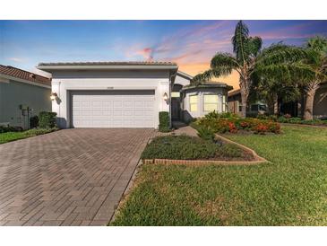 Charming single-story home boasts a brick driveway, two-car garage, and meticulously landscaped front yard at 15528 Corona Del Mar Dr, Wimauma, FL 33598
