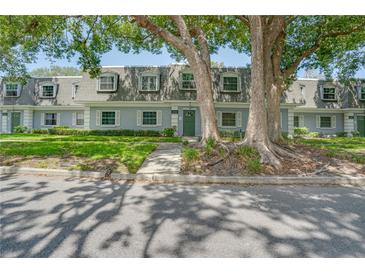 Charming townhouse with dormer windows, surrounded by mature trees and lush landscaping at 1710 Belleair Forest Dr # A, Belleair, FL 33756
