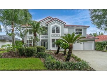 Charming two-story home showcasing a manicured lawn, lush landscaping, and a symmetrical facade at 18110 Courtney Breeze Dr, Tampa, FL 33647