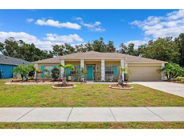 Charming single-story home with a well-manicured lawn, vibrant turquoise accents, and a welcoming front porch at 6724 Clair Shore Dr, Apollo Beach, FL 33572