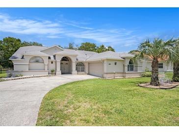 Well-maintained front yard with a circular driveway and manicured landscaping that enhance the home's curb appeal at 14181 Cornewall Ln, Spring Hill, FL 34609