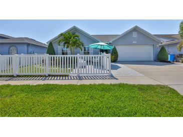Charming home with a white picket fence, lush lawn, tropical palm, and welcoming outdoor seating area at 214 Lookout Dr, Apollo Beach, FL 33572
