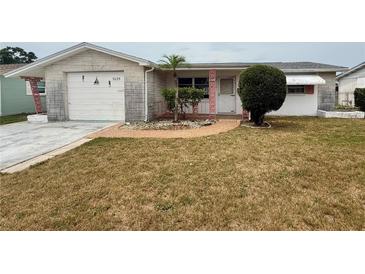 Charming single-story home with a well-maintained front yard and decorative brick pathway at 3035 Coldwell Dr, Holiday, FL 34691