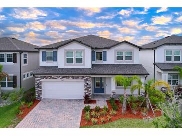 Two-story home featuring a brick-accented garage, well-manicured landscaping, and a contrasting front door at 3063 Marine Grass Dr, Wimauma, FL 33598