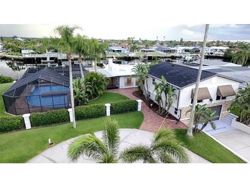 Stunning waterfront home with a screened pool, lush landscaping, and circular driveway at 3654 Corsair Ct, New Port Richey, FL 34652