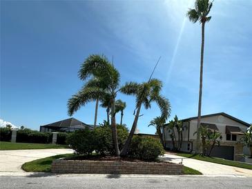 Beautiful home featuring well-maintained landscaping, palm trees, and lush greenery against a clear blue sky at 3654 Corsair Ct, New Port Richey, FL 34652