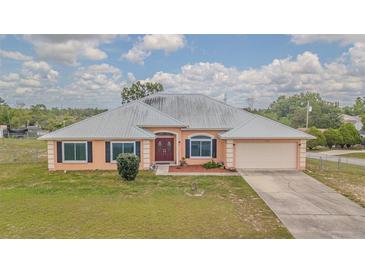 Inviting single-story home featuring a metal roof, double door entry, and attached two car garage at 5432 Queen Ave, Spring Hill, FL 34609